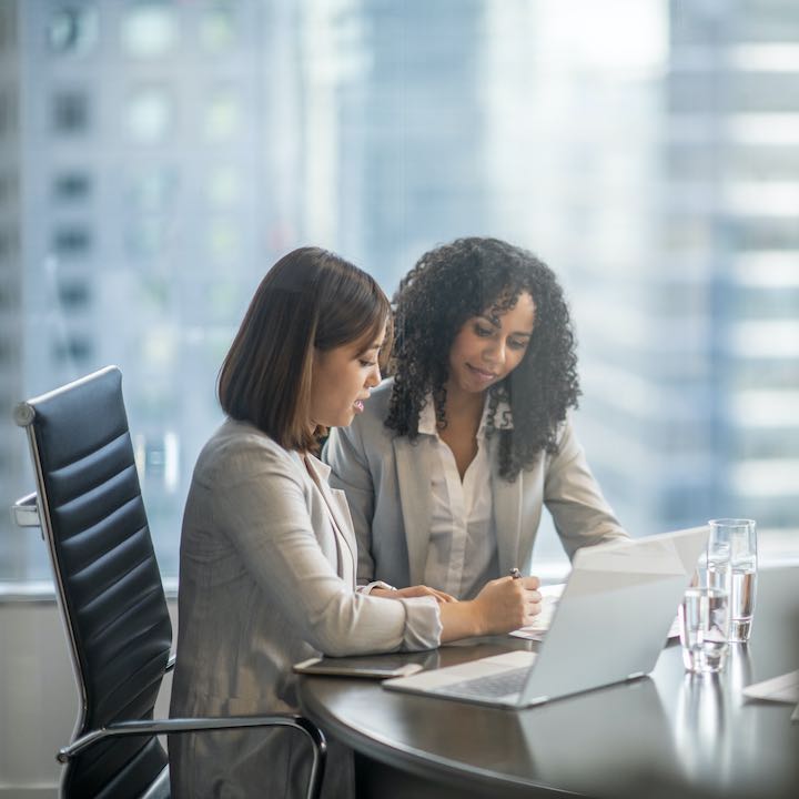 two women discussing document in large office