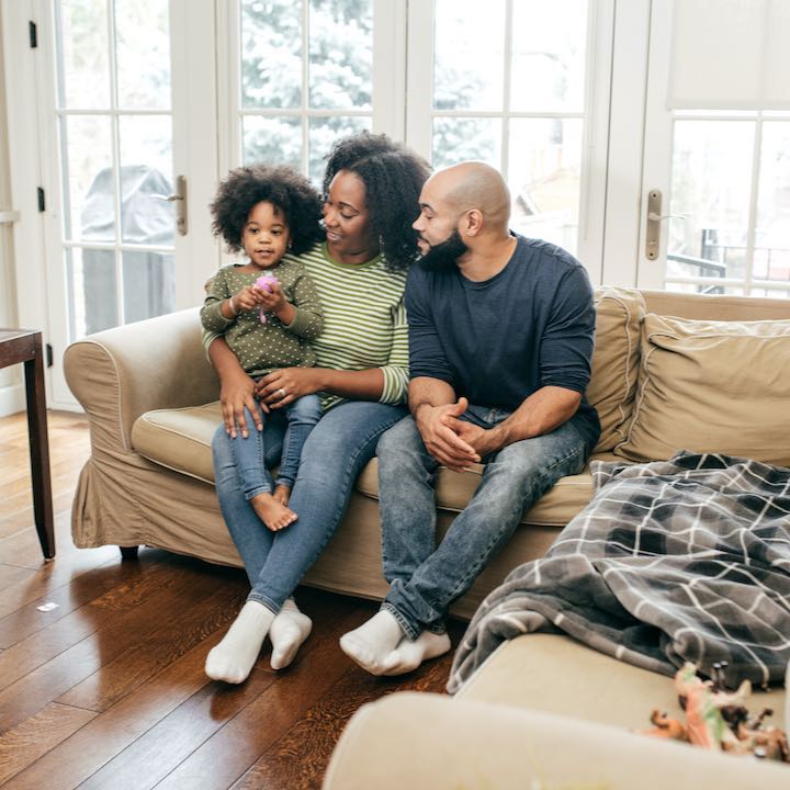 parents with little girl sitting on couch