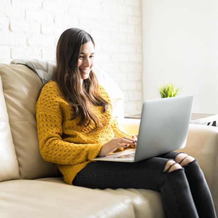woman sitting on couch using laptop