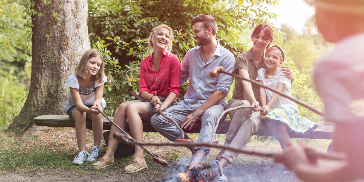 family roasting hot dogs over a fire