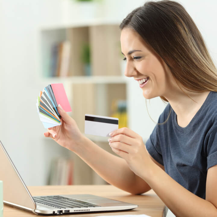 woman holding credit cards looking at laptop