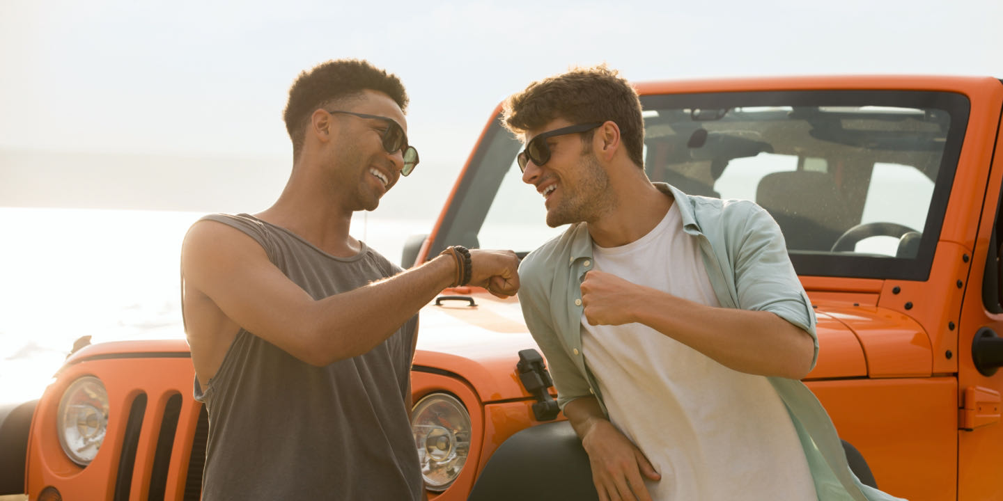 two guys fist pump by jeep on beach