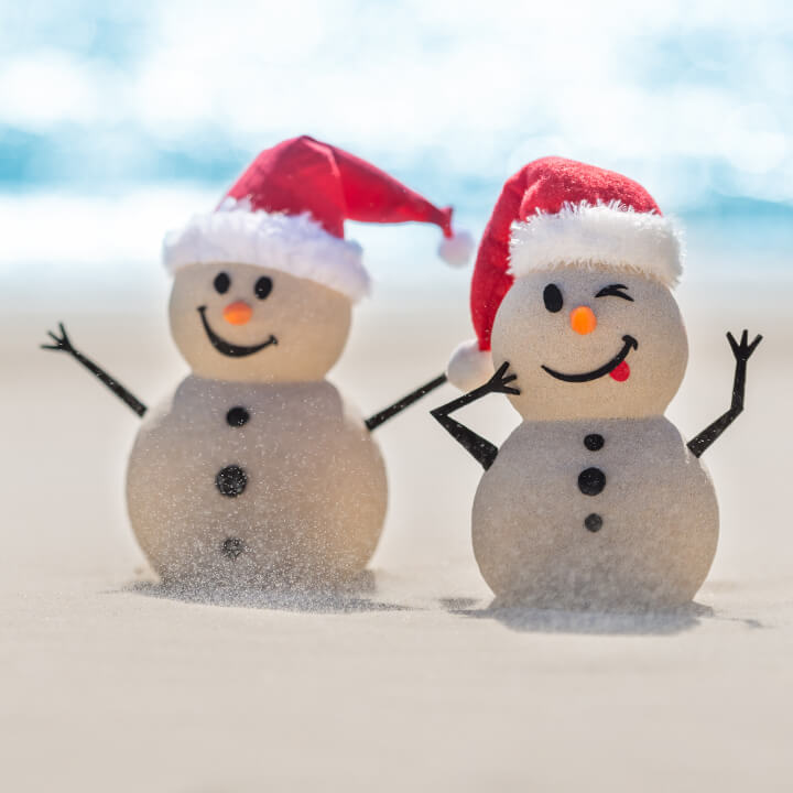 two Santa snowmen made of sand on beach