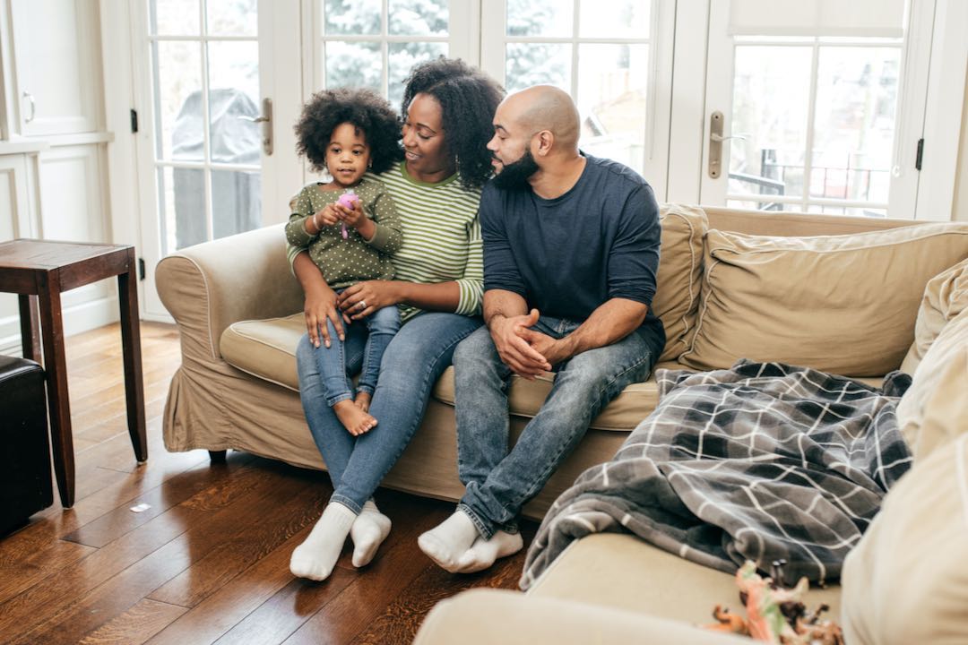 parents with little girl sitting on couch